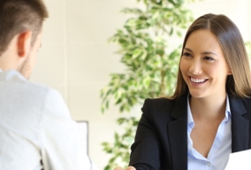 Male job candidate shaking hands with female employer at a job interview 