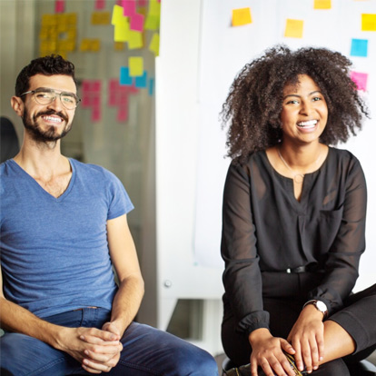 Two colleagues in a meeting. They're both smiling.