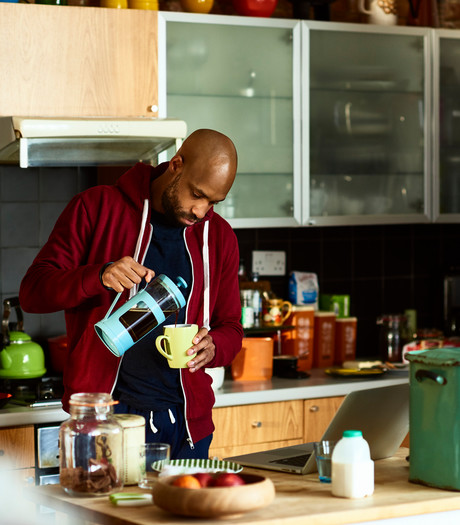 A young man pouring coffee in his kitchen 